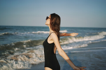 pretty woman in black swimsuit posing sun walking on the beach