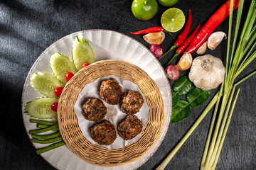Top view of Thai Traditional cuisine, Tasty Thai style Fried Pork or meat Balls with Garlic. A Delicious recipe from Asia ingredients on a rustic black dark wooden table.Thailand restaurant food menu