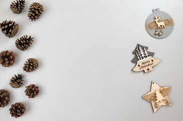 Wooden Christmas decorations and pine cones on gray background, top view, flat lay, copy space for text.