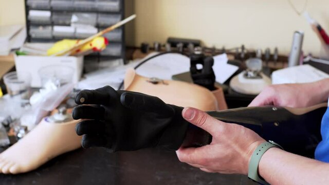A medical prothetics techinican demonstrates a modern artifical bionic arm prothesis in the laboratory. An artificial hand moves black fingers