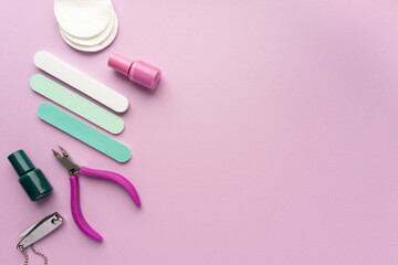 Flat lay of manicure accessories with nail polishes on lilac background, space for text