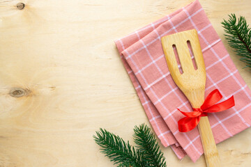 Christmas composition. Kitchen spatula and towel on wooden background, space for text