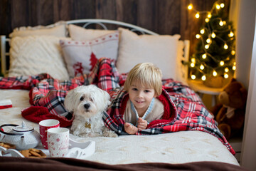 Cute toddler child, boy in a christmas outfut, playing in a wooden cabin on Christmas, derocation around him