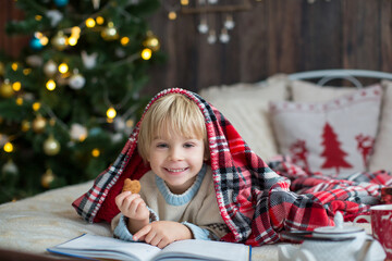 Cute toddler child, boy in a christmas outfut, playing in a wooden cabin on Christmas, derocation...