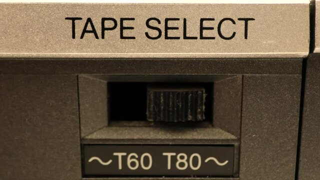 Extreme close up of buttons on an old antique or vintage VCR a switch going from a T60 tape to a T80 Tape flipping the switch