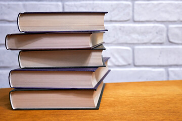Stack of books close-up on wooden table against wall background