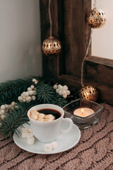 a cup of coffee with white berries, spruce branches, a garland and marshmallows