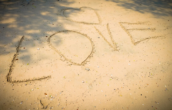 handwriting text LOVE on sand, With color effect
