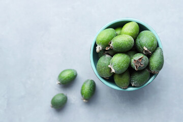 Green feijoa fruits in a bowl on a gray concrete background. Space for copying. Selective focus. Top view
