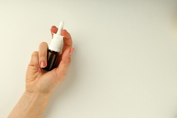 Female hand holds blank bottle of nasal spray on white background