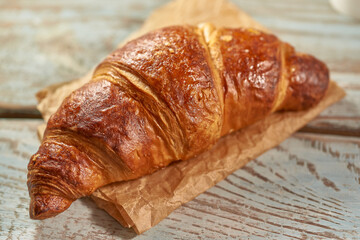 Morning croissant and a cup of coffee on a wooden background