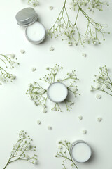 Eco lip balm and flowers on white background