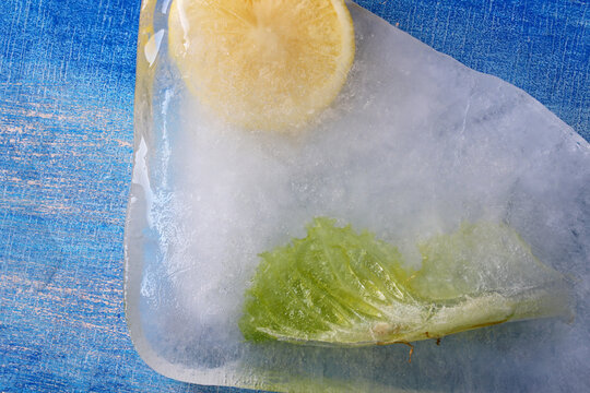 A Slice Of Lemon And Lettuce Frozen On Ice