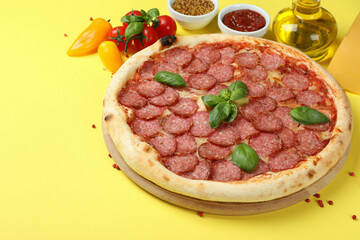 Concept of tasty food with Salami pizza on yellow background