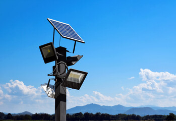 Photovoltaic panel systems and hd floodlights on black metal pole in public park, soft and selective focus.