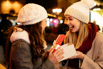 Portrait of happy women friends exchanging christmas present. Holiday people happiness concept
