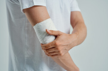 male patient in a white T-shirt with a bandaged hand light background