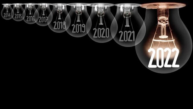 Shining light bulb with New Year 2022 and group of dark light bulbs in a row going from 2014 to 2021 isolated on black background. Seamless looping. High quality 4k video.