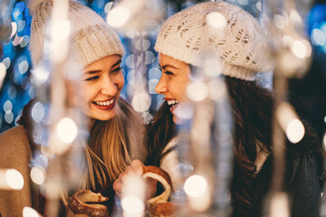 Happy women friends having fun, enjoying moments together in christmas decorated background.