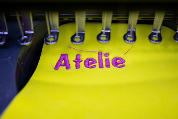 Professional embroidery machine that embroiders 3D design on yellow puff. Inscription Atelie