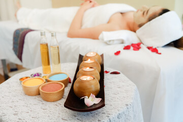 Fototapeta na wymiar spa composition set and young woman lying in bed and relaxing in massage room