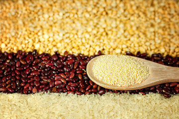 Food background. Crushed dry peas, red beans, rice, couscous on a wooden spoon. 