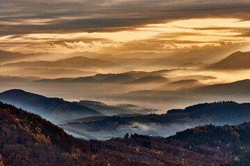 Autumn mountain misty landscape at dawn. View of the valley from Vrsatec hill, Slovakia. Morning soft light. with colored skies and clouds. Hills in the fog. 