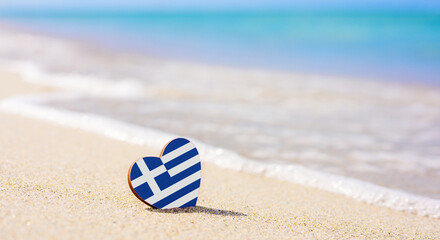 Flag of the Greece in the shape of a heart on a sandy beach. The concept of the best vacation in...