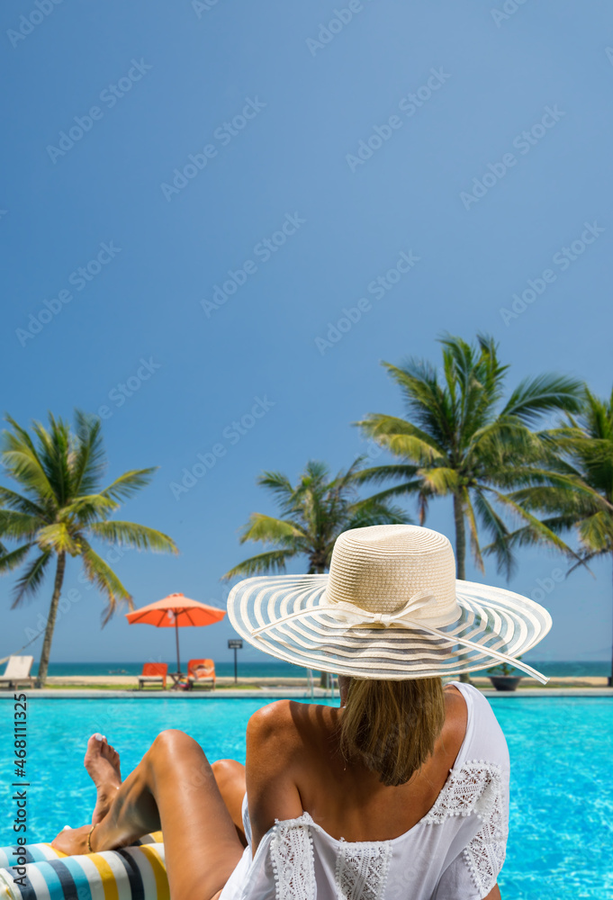 Wall mural woman in luxury spa resort near the swimming pool.