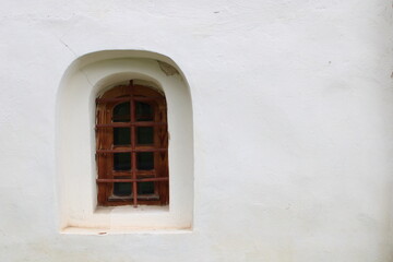 Fototapeta na wymiar window with metal bars in the ancient white wall