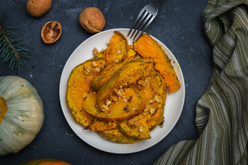 Plate of baked pumpkin sprinkled herbs and walnuts. Thanksgiving day meal. 