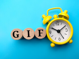 Alarm clock and block cylinder with word GIF on blue background.