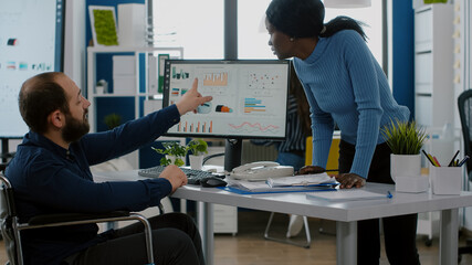 Corporate business people discussing in financial start up business office, african manager showing ideas to handicapped employee immobilized in wheelchair, explaning strategy, sharing problem,