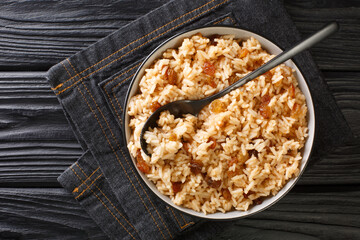 Coconut pilaf rice with raisins close-up in a bowl on the table. horizontal top view from above