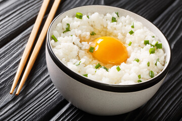 Tamago kake gohan is a simple Japanese dish made of raw Egg Over Rice close up in the bowl on the table. Horizontal