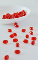 Soft gels of Gac oil or Momordica cochinchinensis oil on a spoon against white background