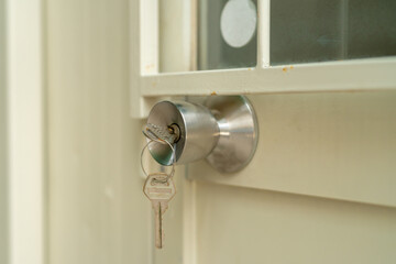 Closeup, the key is inserted on the silver doorknob. which is installed on the iron gate with cream color