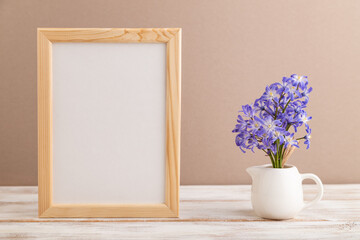 Wooden frame with spring snowdrop flowers chionodox on beige pastel background. top view, copy space, mockup, template.