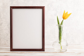 Wooden frame with orange tulip flower in glass on gray concrete background. side view, copy space, mockup.