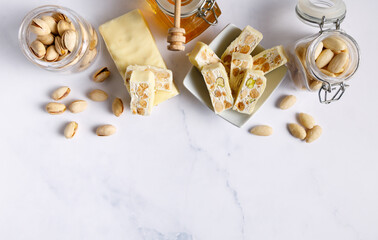 Fototapeta na wymiar White chocolate covered nougat. Nougat with pistachios and almonds. These delicious confections are filled with the dried almonds and pistachio nuts and covered with white chocolate.
