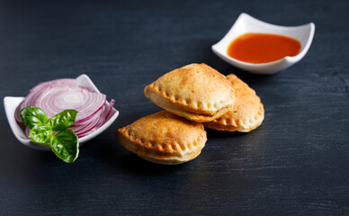 Homemade empanadas with sauces. South American street food. These delicious beef empanadas are mandatory to eat, they have a crunchy dough and an exquisite ground beef filling.
