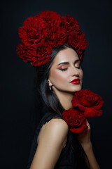 Beauty portrait brunette woman with crown of roses flowers on her head. Bright red makeup and lipstick. Rose flowers in the hands of a woman © angel_nt