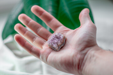 Natural minerals in a man's hand. Stones on a white rag background with green leaves.