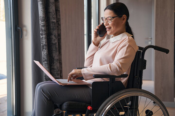 Happy mature woman with disability making call indoors