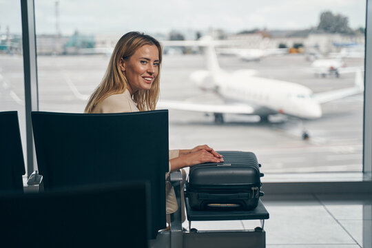 Cheerful traveler with luggage sitting in airport lounge