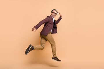 Fototapeta na wymiar Full length body size profile side view of attractive cheery man jumping running promotion motivation isolated over beige color background