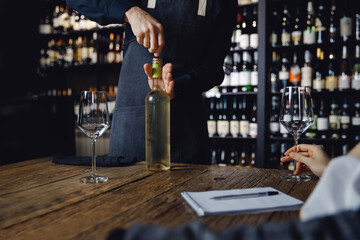 Preparing for tasting white wine in restaurant, sommelier takes cork from bottle