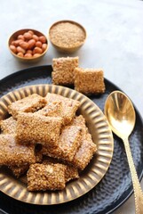 Indian makar sankranti festival food oe sweets. Tilgul in a small brass plate. Tilgul is made out of sesame seeds, peanuts, and jaggery. Til gul ki chikki or sesame candy. Copy Space. Winter food.