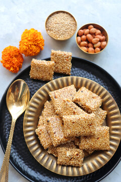 Indian makar sankranti festival food oe sweets. Tilgul in a small brass plate. Tilgul is made out of sesame seeds, peanuts, and jaggery. Til gul ki chikki or sesame candy. Copy Space. Winter food.