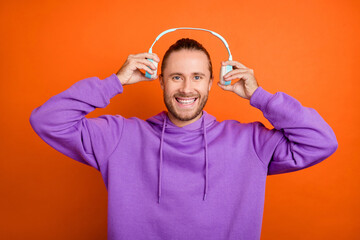 Photo of nice millennial brown tail hairdo guy listen music wear purple hoodie isolated on orange color background